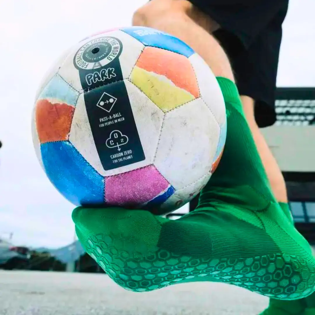 Grip Socken in grüner Farbe. Fußballspieler jongliert mit Ball.