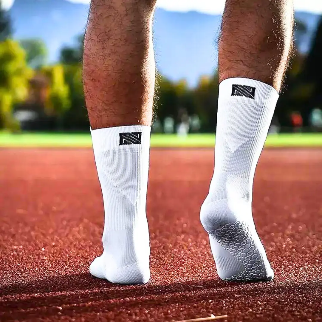 Grip Socken in weißer Farbe. Fußballspieler läuft auf dem Tartanplatz.